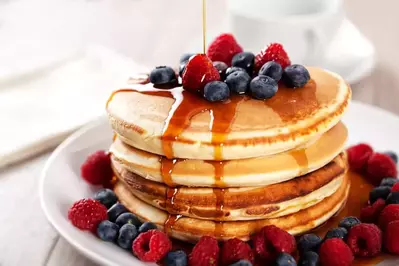 stack of pancakes with berries and syrup